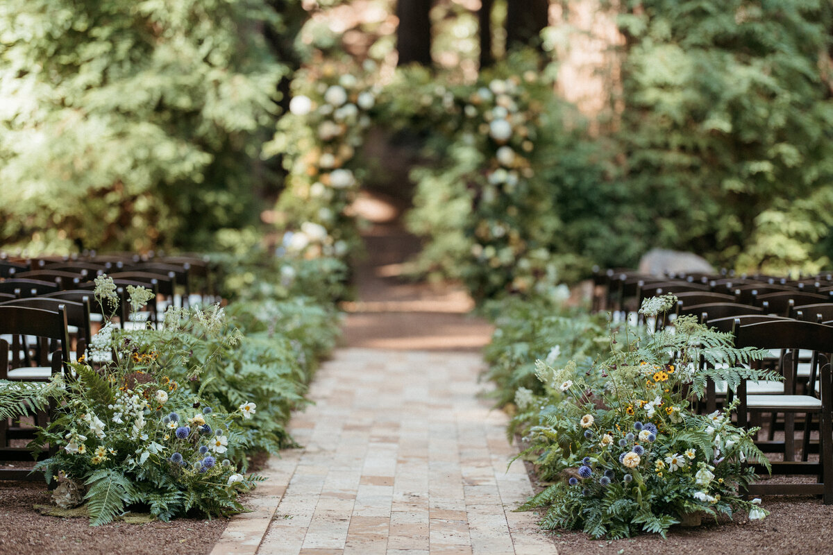 Forest floor-inspired fern and wildflower wedding ceremony aisle.