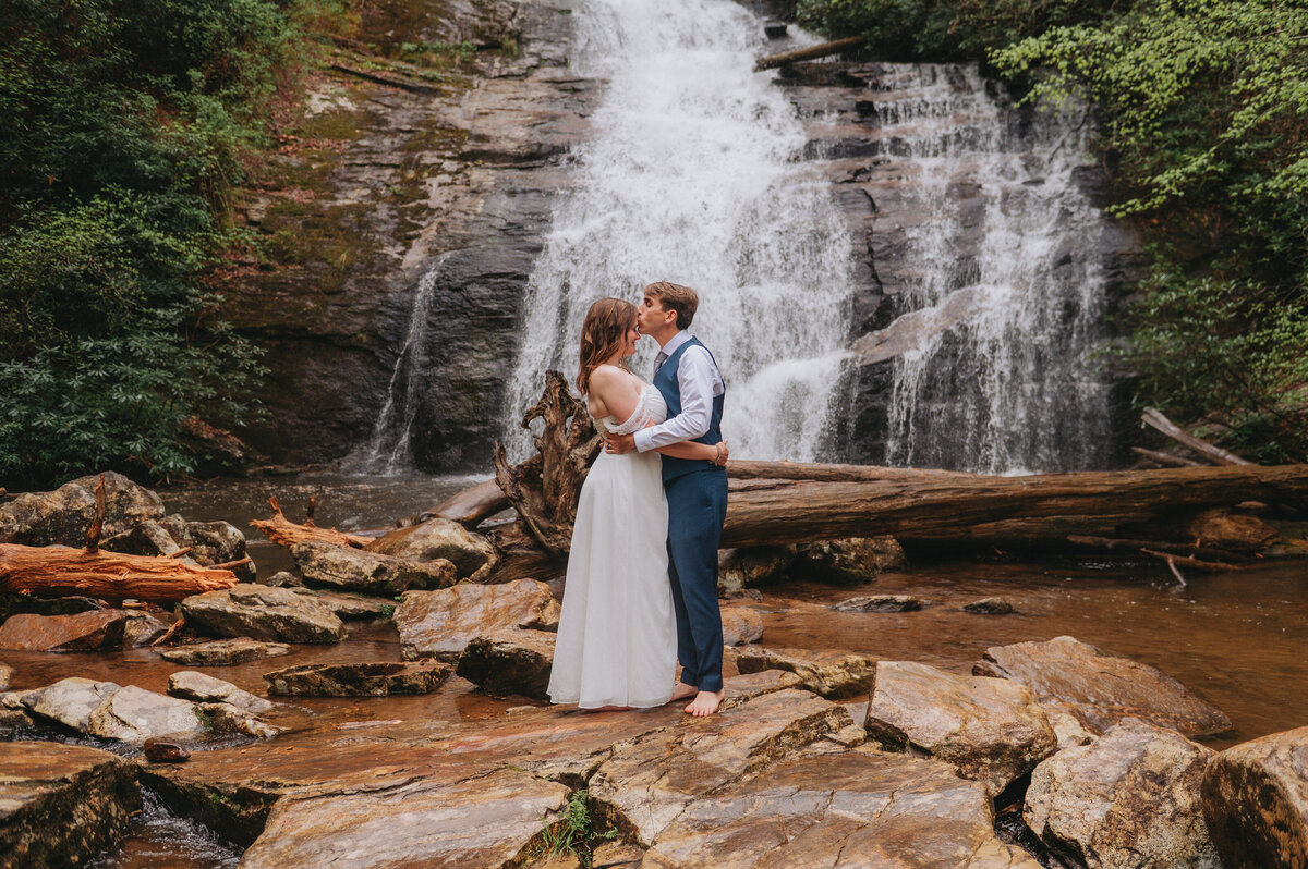 Newlyweds kiss in front of a waterfall