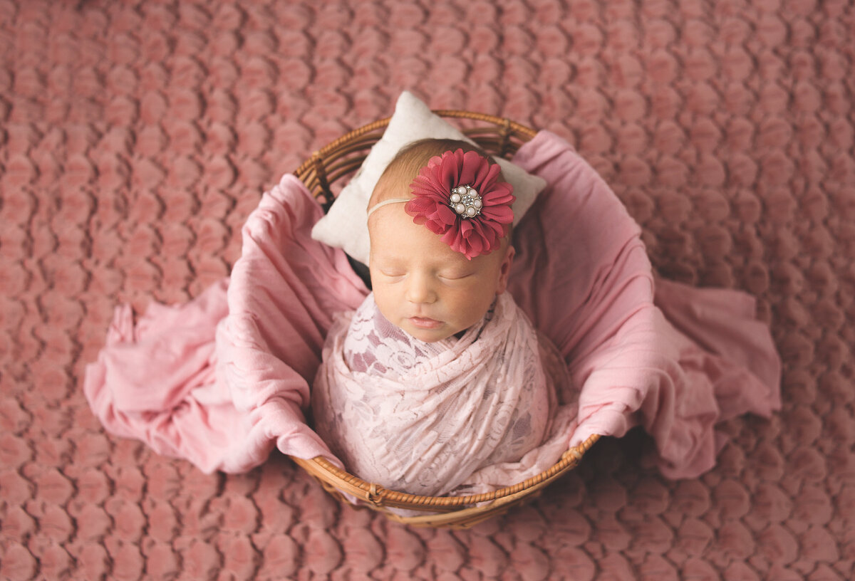 Baby girl wrapped in pink lace laying in basket during newborn session photoshoot in Franklin Tennessee photography studio