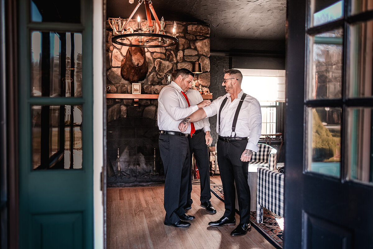 Groomsman helping groom get ready in cabin at Wentworth Inn in Jackson NH by Lisa Smith Photography