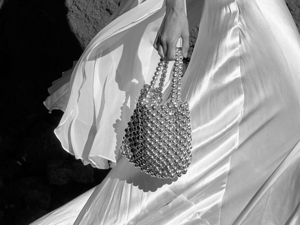 Bride holding a silver bag in her hands while walking