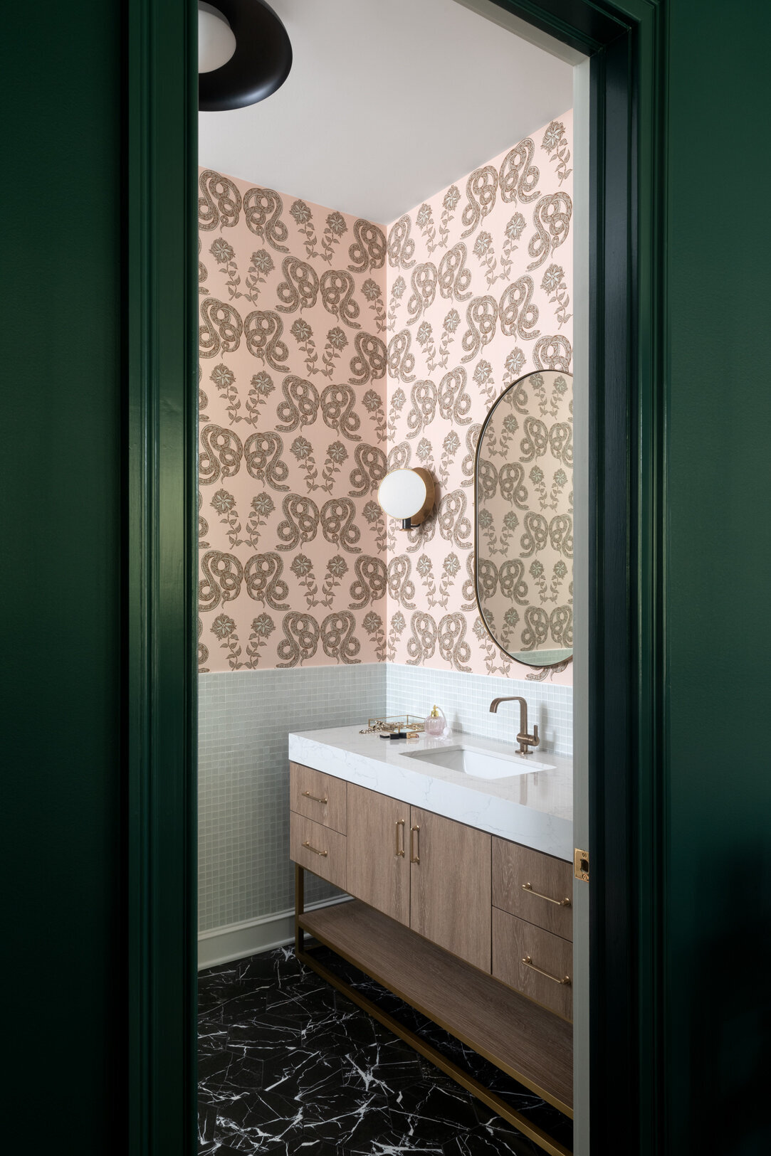 dark olive green door opening to a light pink patterned bathroom with white and wood sink