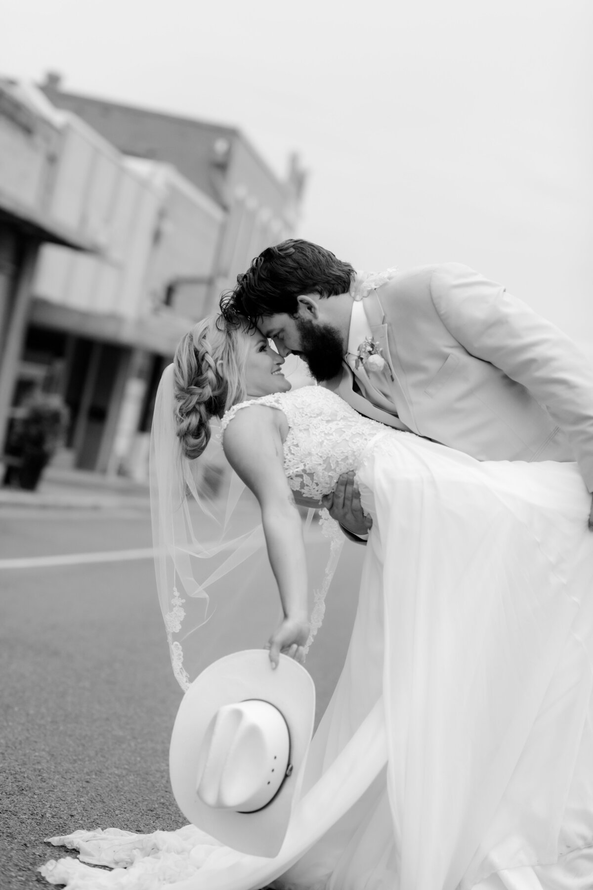 black and white wedding portrait of groom dipping his bride backwards as they stand in the middle of the road in down town little rock