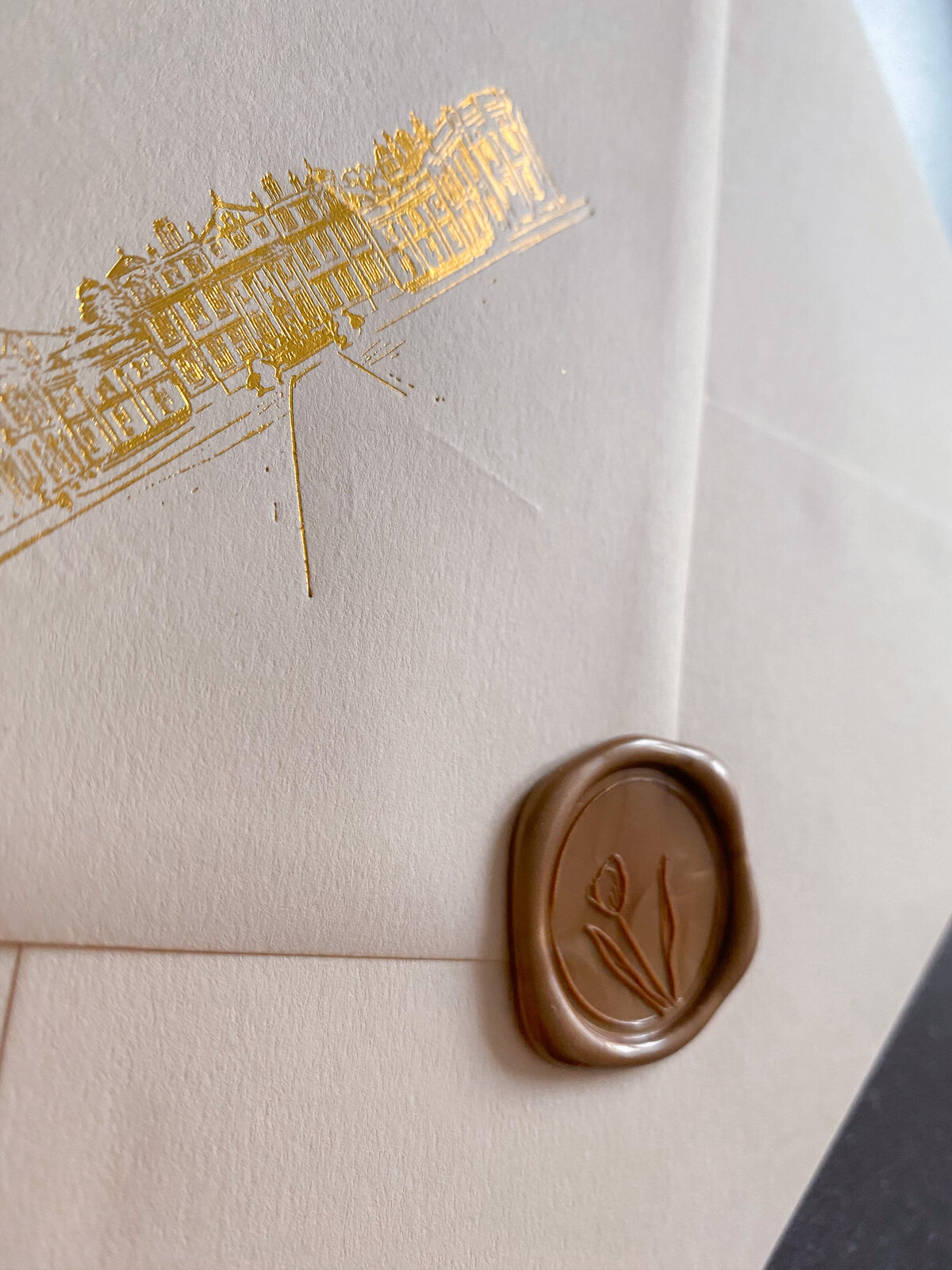 Envelope sealed with a wax seal, and a foil illustration of a venue