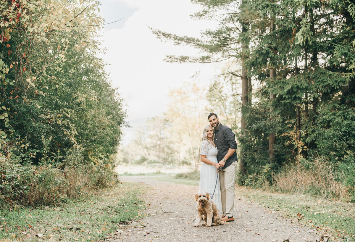 Couple posing with their dog at their sunset engagement session in London Ontario