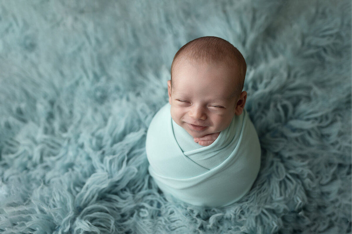 Smiling baby boy wrapped in blue.