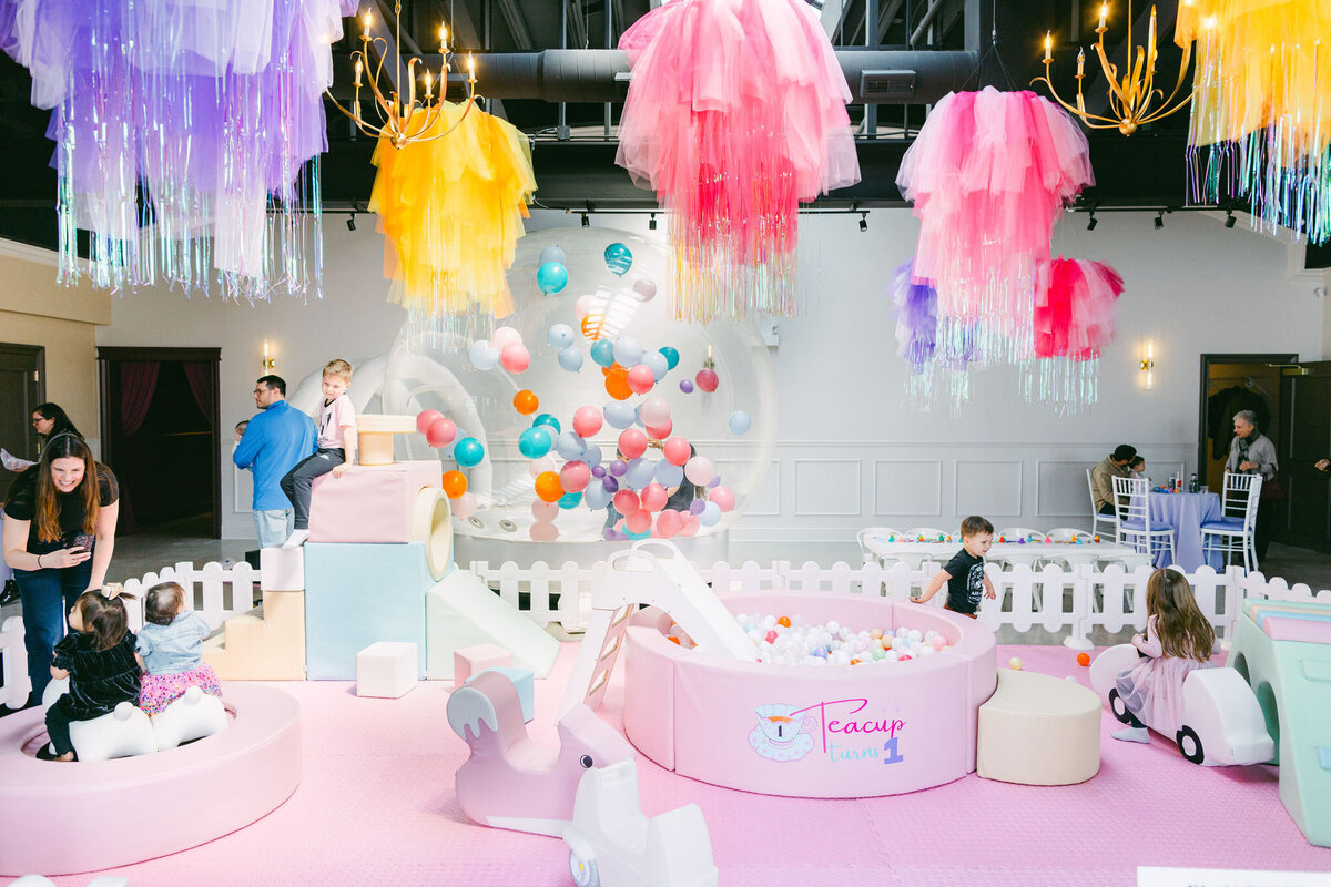 Colorful bounce house at a children’s birthday party venue, surrounded by vibrant balloons, playful decorations, and festive table settings, creating a fun and lively atmosphere