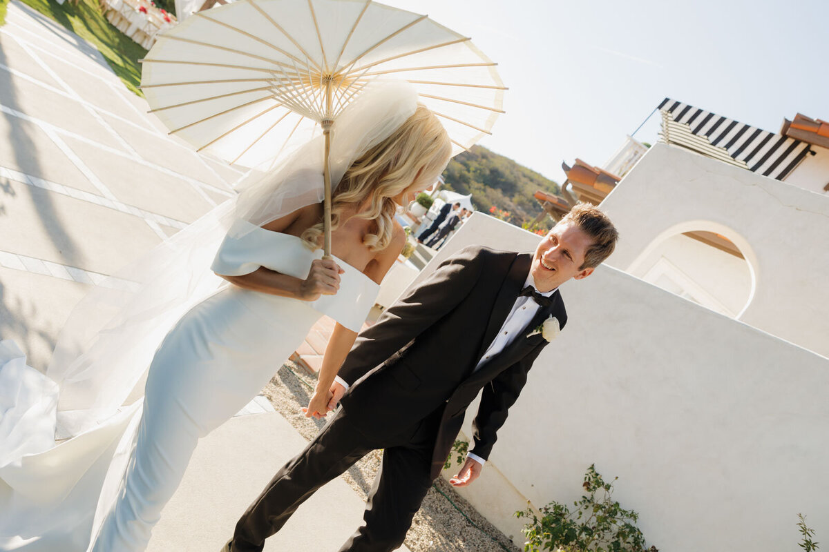Bride and groom dancing gently on rock by water