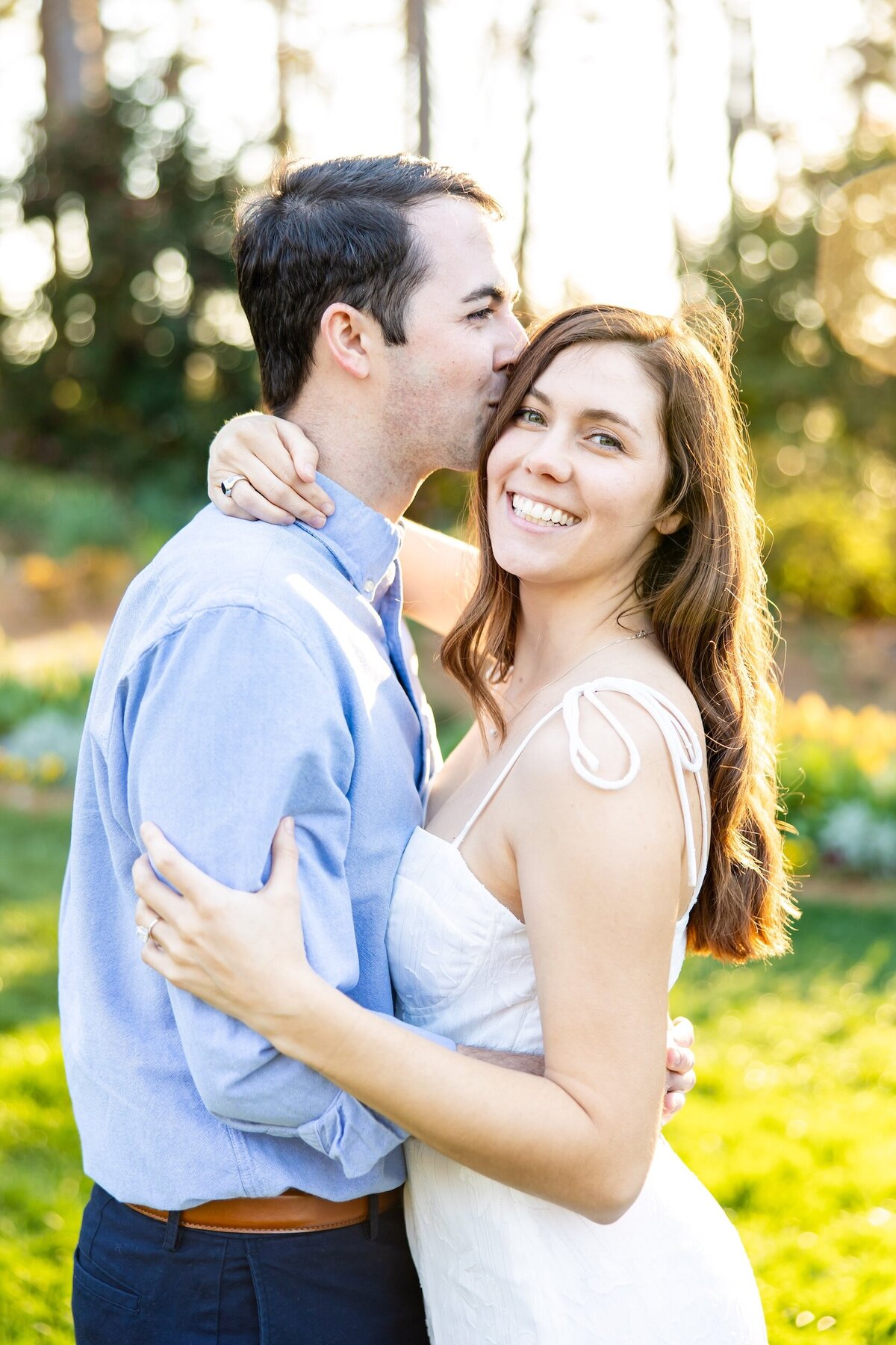 Man kissing his bride to be on the side of her head