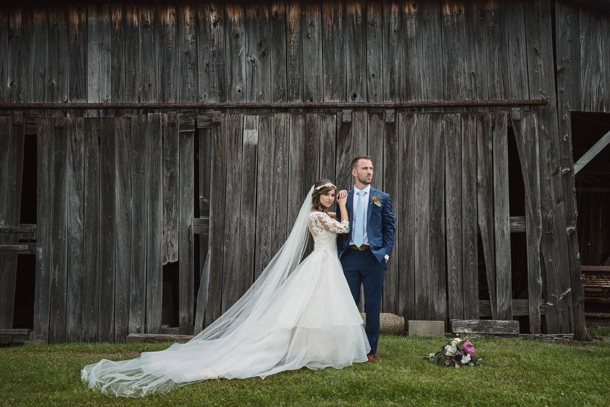Bride and groom by barn.