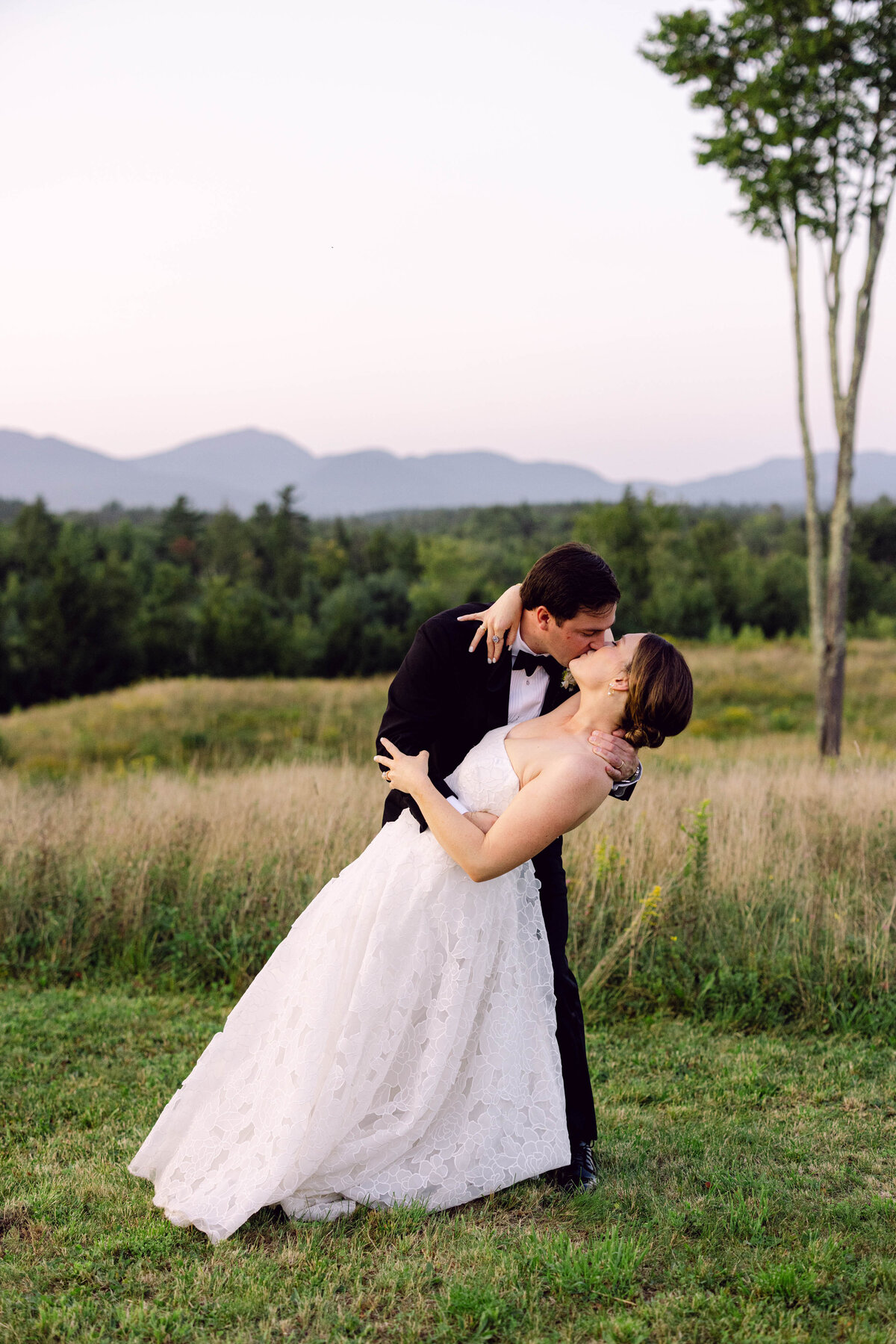 bride and groom kissing in field