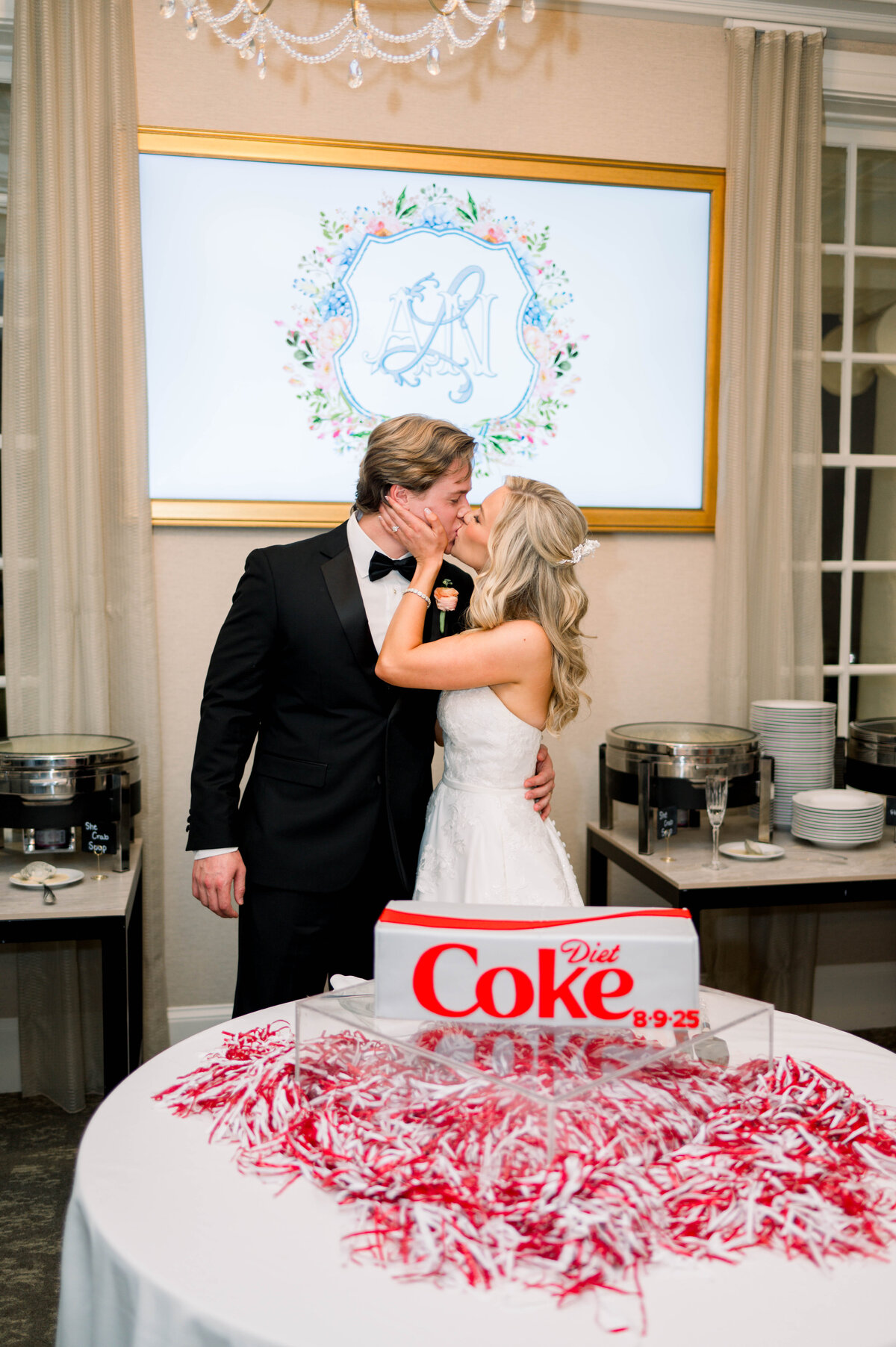 Couple kissing with groom’s cake shaped like Diet Coke can at University Club summer wedding
