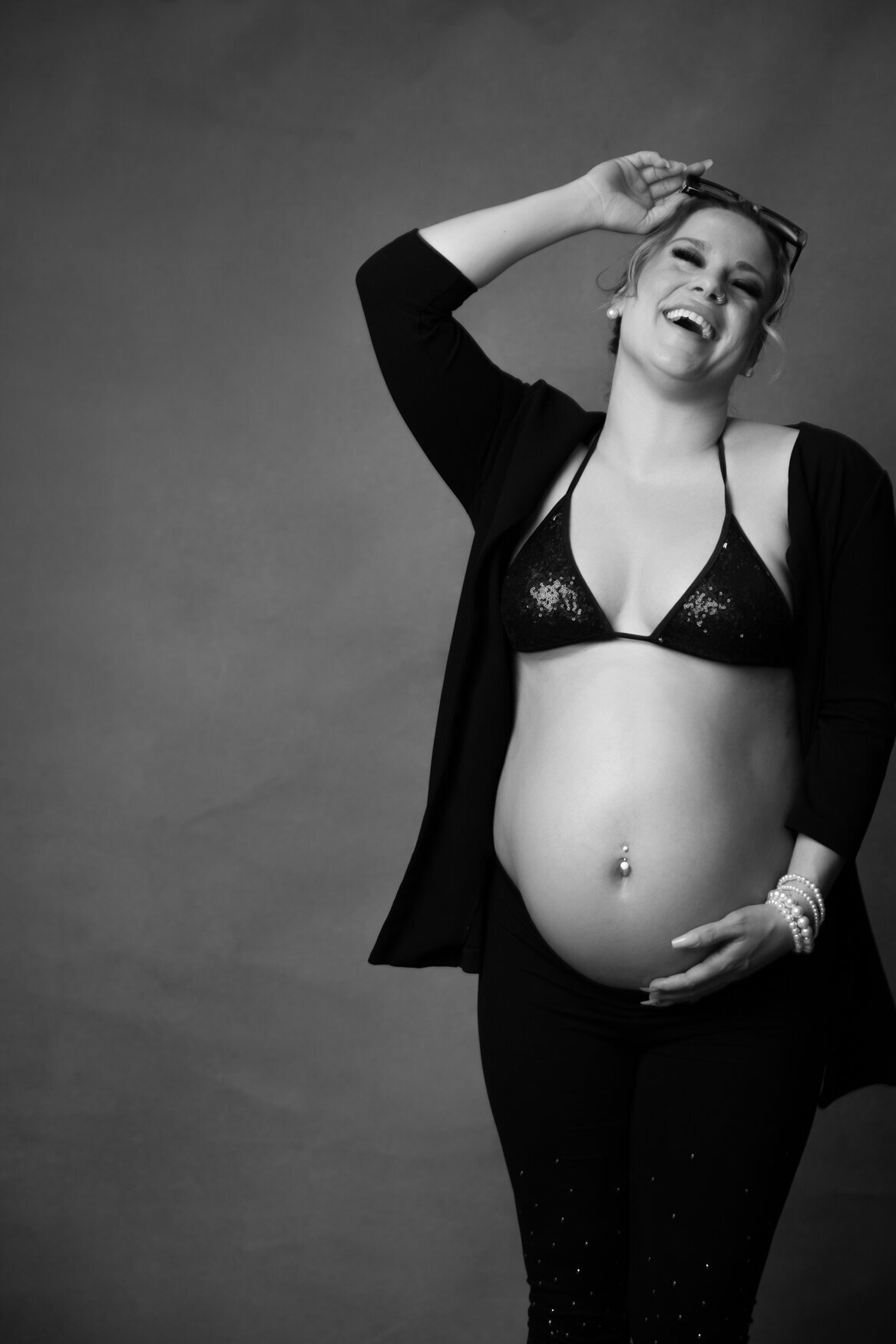 A woman smiling showing her pregnant belly to the camera