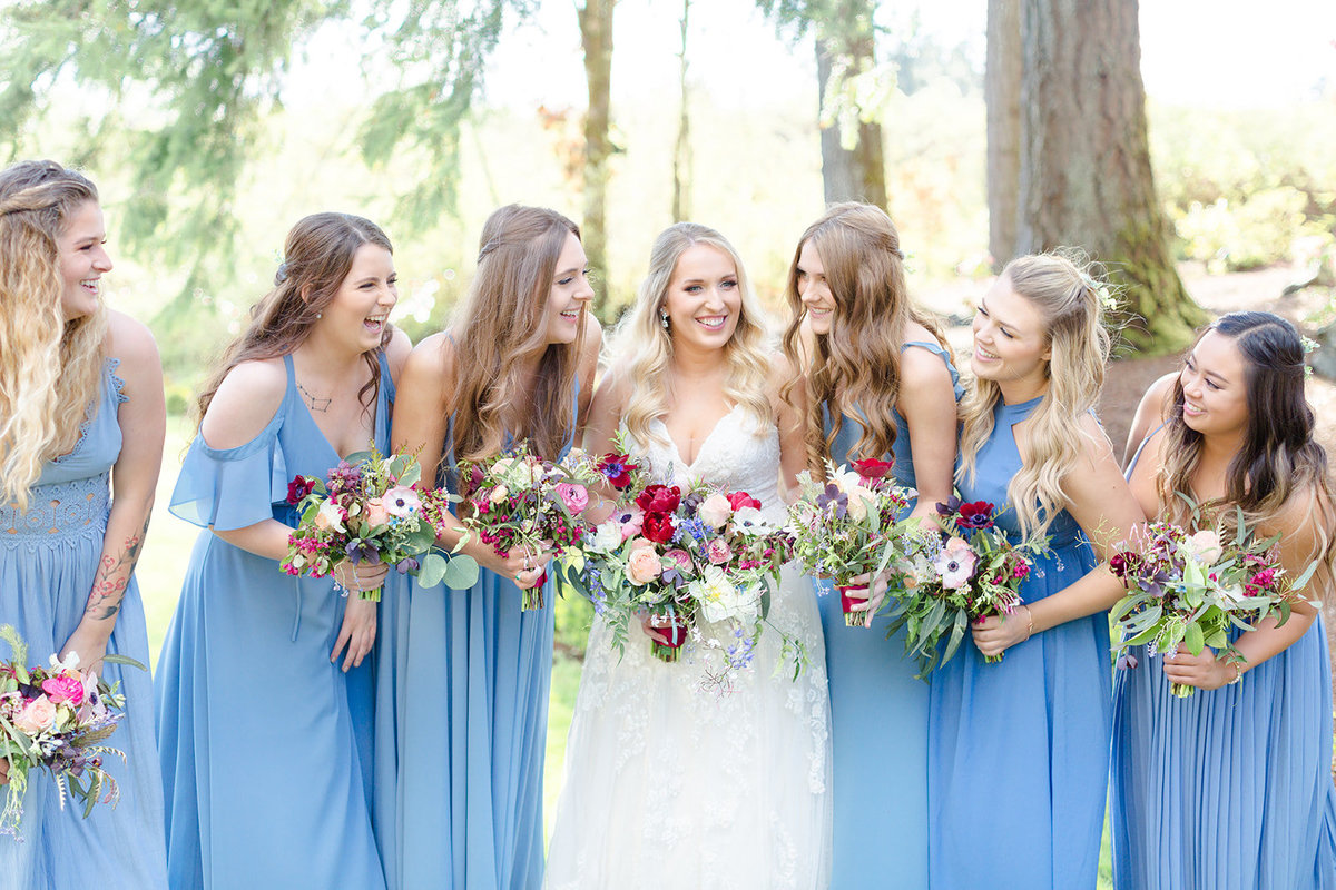 bridesmaids laughing and  holding wild flower bouquets