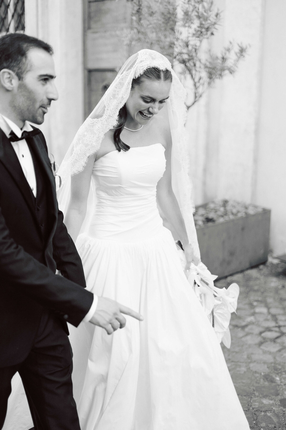 Bride and groom walking hand in hand over cobblestone street in Rome

