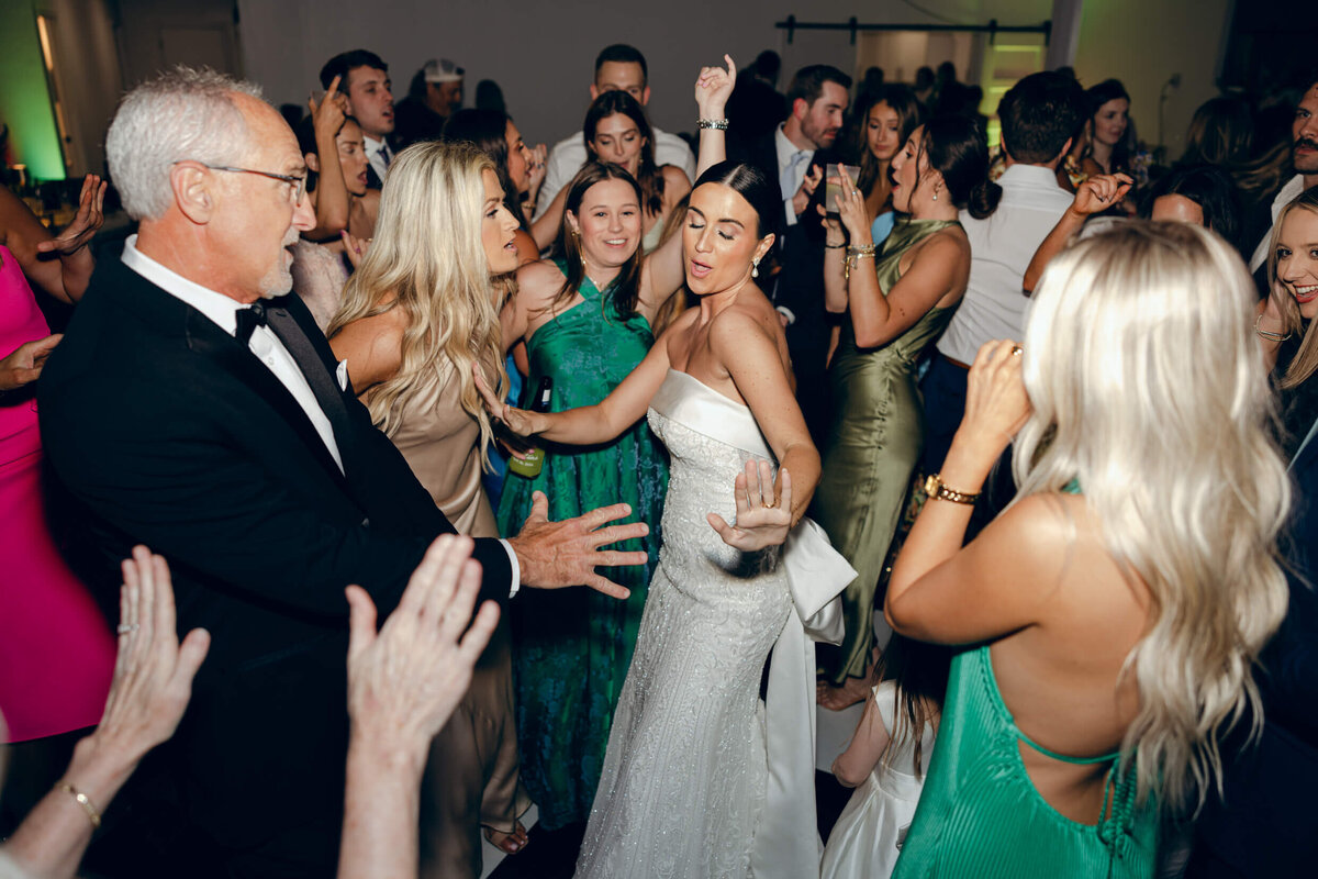 A candid wedding photo of the bride dancing at her wedding reception surronded by her wedding guests