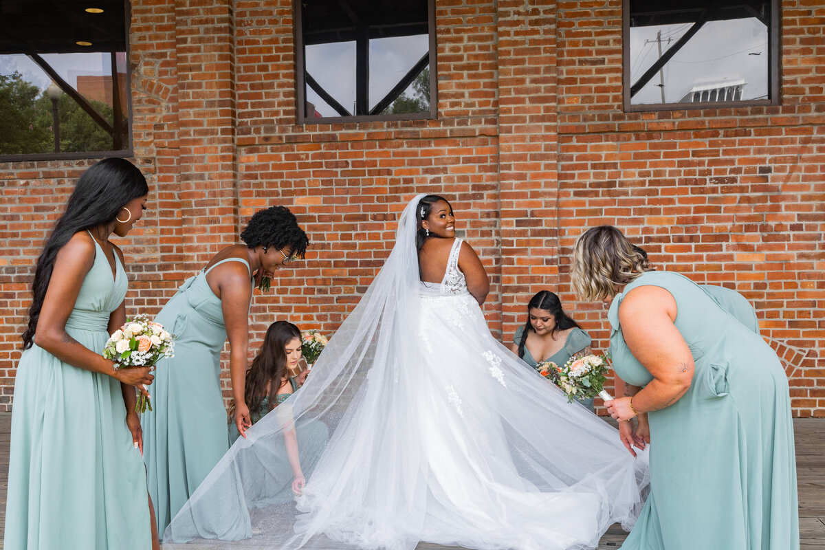 bridesmaids fixing brides dress at Columbus Georgia trade and convention center by Georgia wedding photographer Amanda Richardson Photography