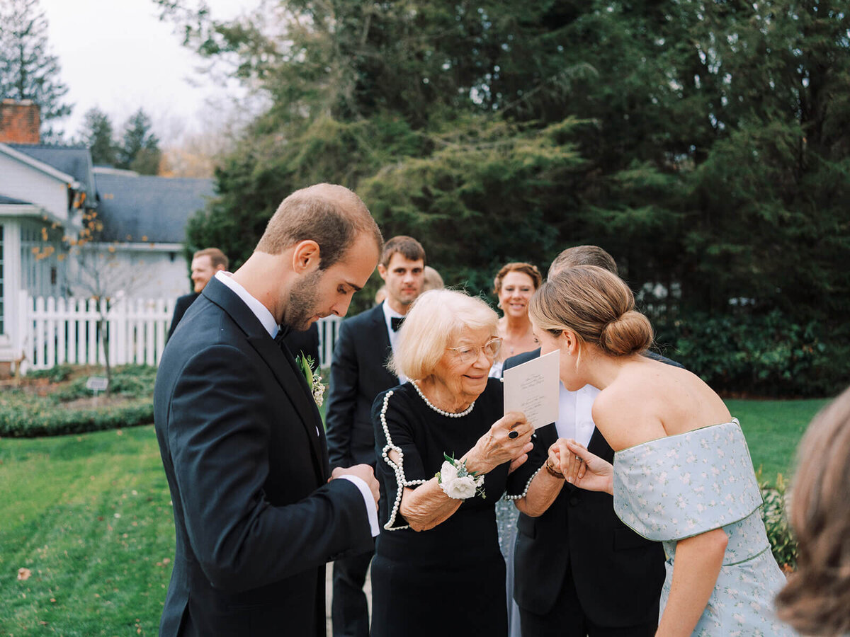 14. Family greeting an elderly guest outdoors during a wedding.