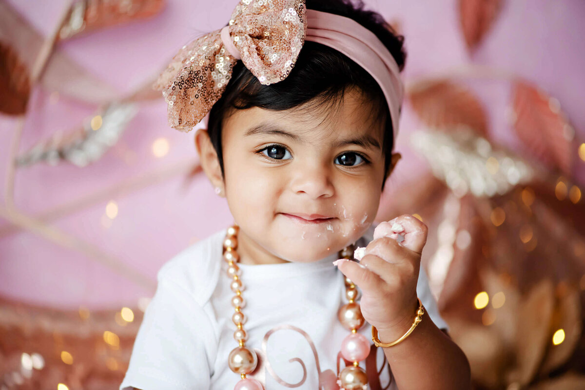 up-close photo of a little girl wearing a pink headband for her cake smash photography session 