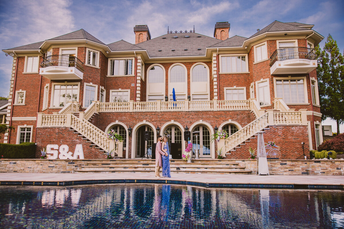 an indian bride and groom share a moment at their sangeet by the pool behind a large mansion