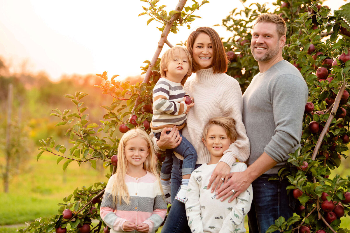 Close up of mom and dad with their three kids in an apple orchard for their Burlington family photos 