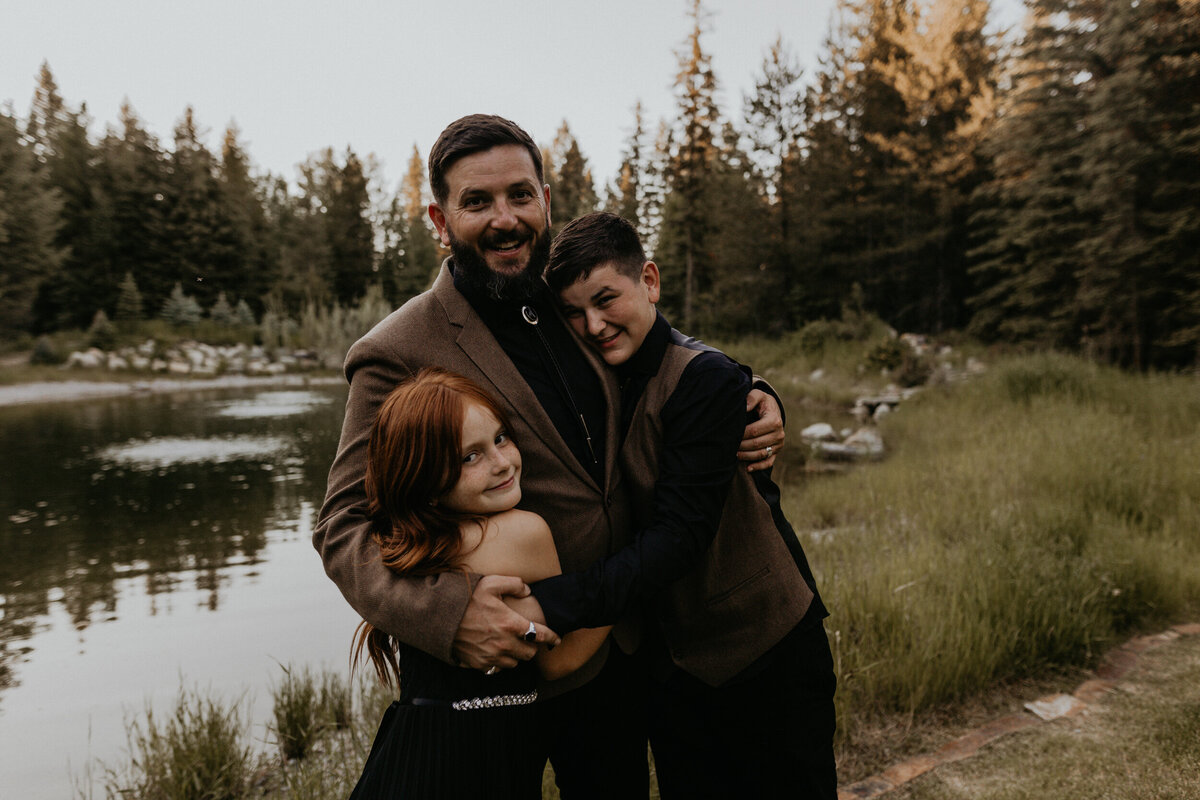 groom with his kids in front of a pond