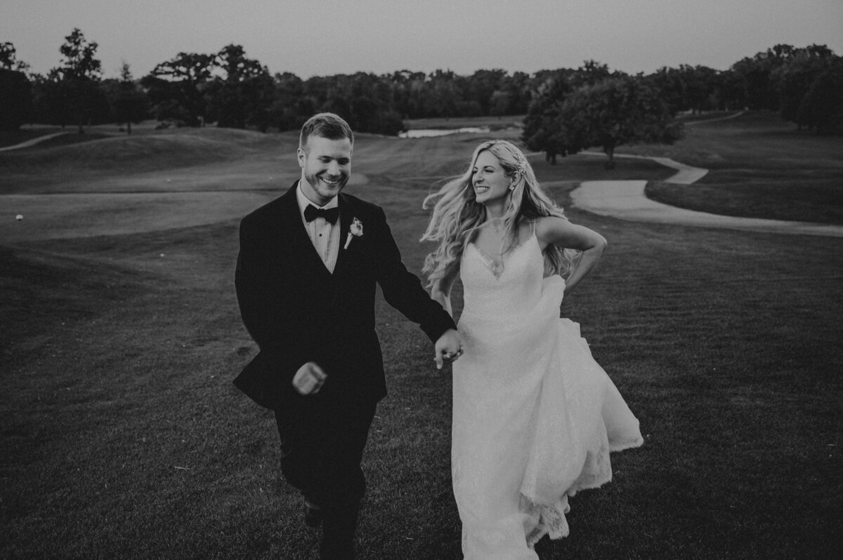 Bride and Groom running and smiling on golf course