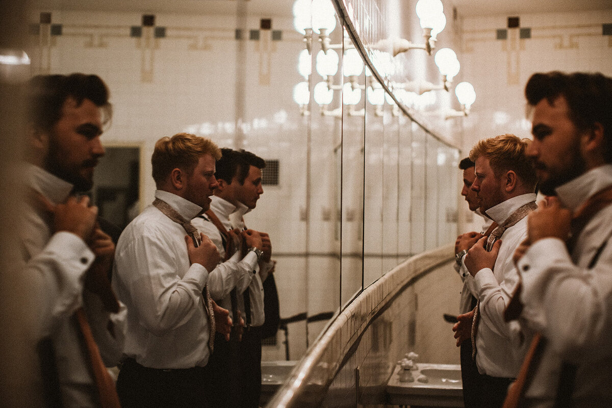 groomsmen get ready in vintage barber shop mirror 