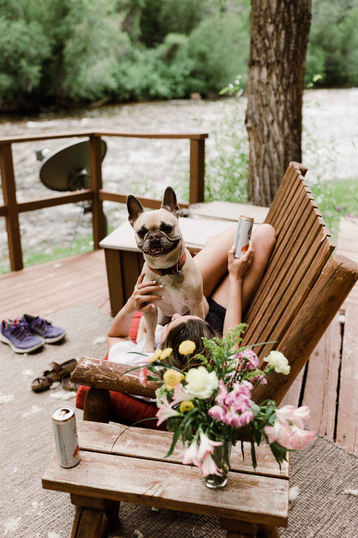 Dog sitting on lap of a woman with bouquet of flowers sat on a table