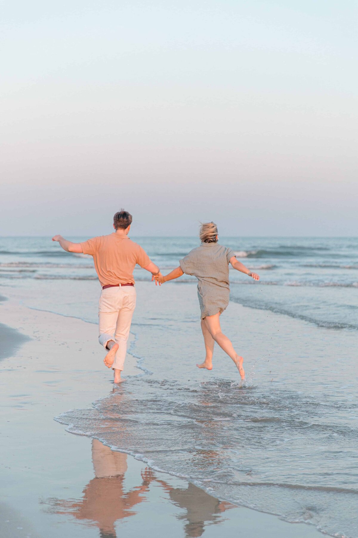 A young couple holding hands running on the beach in Hilton Head, SC with Hilton Head Photographer, Lamp and Light Photography