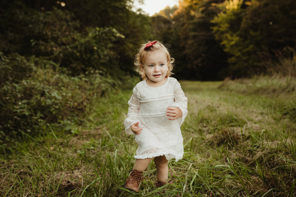 A little girl wanders down a grassy trail.
