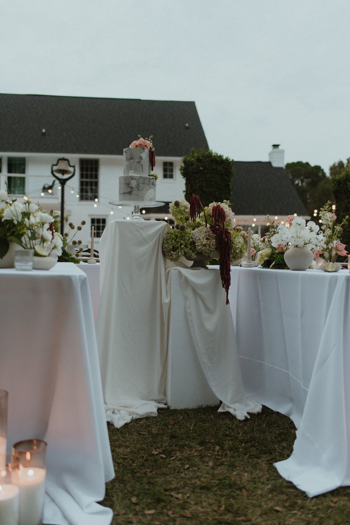 Tiered wedding cake with floral accents on white pedestal