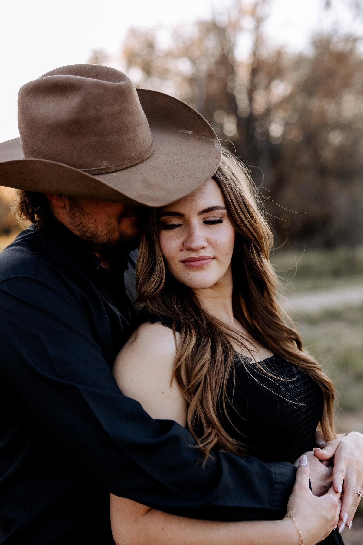 dad in cowboy hat embracing his wife who is  wearing a  black dress. 