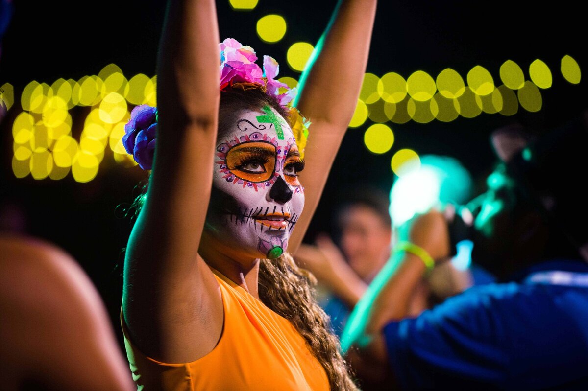A women's face surrounded by lights performs at day of the dead party for event attendees