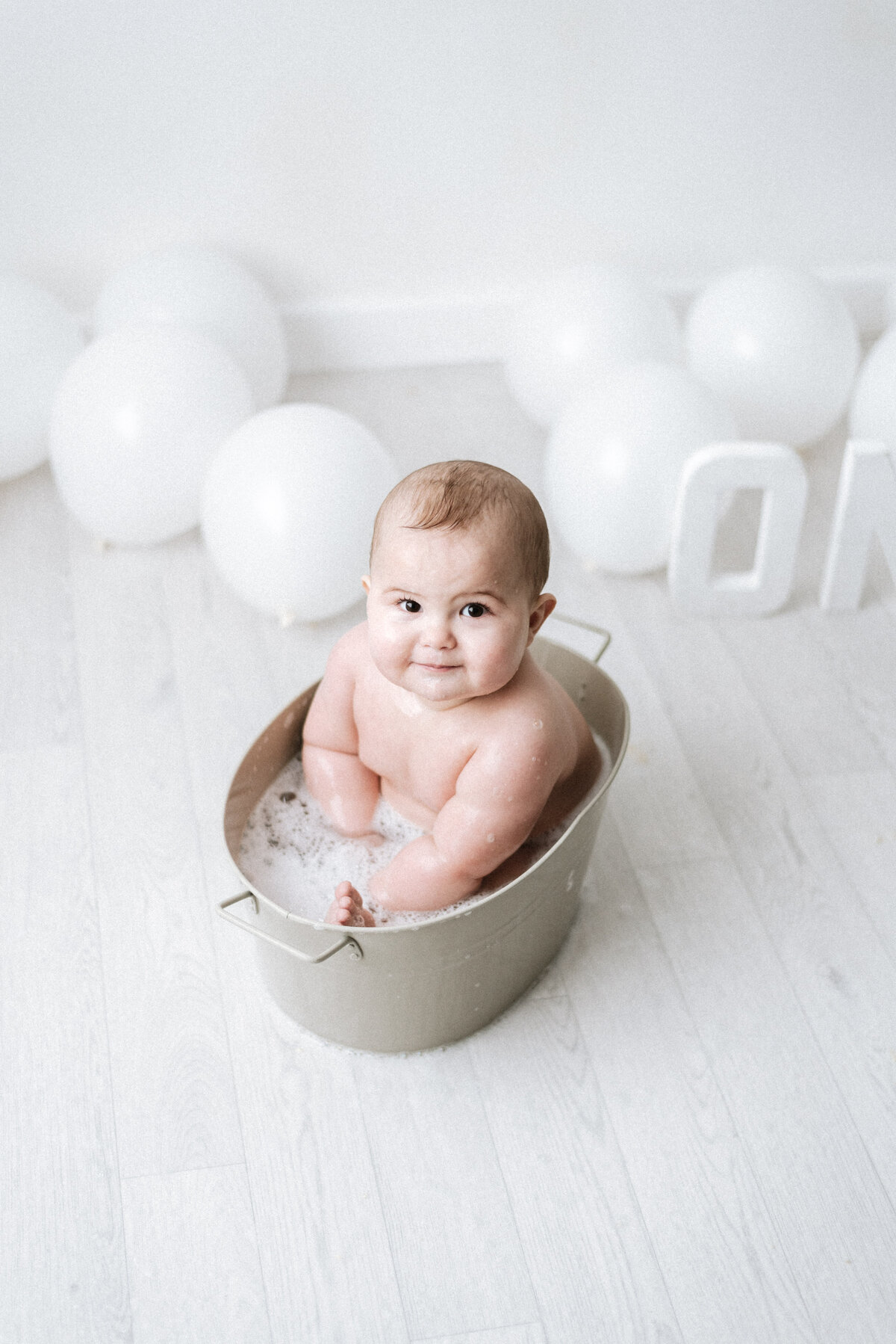 Baby boy smiling in a bath tub at west sussex cake smash photoshoot