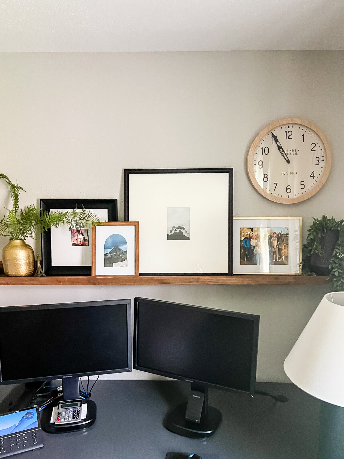 An open shelf displays several framed photos above a home office desk