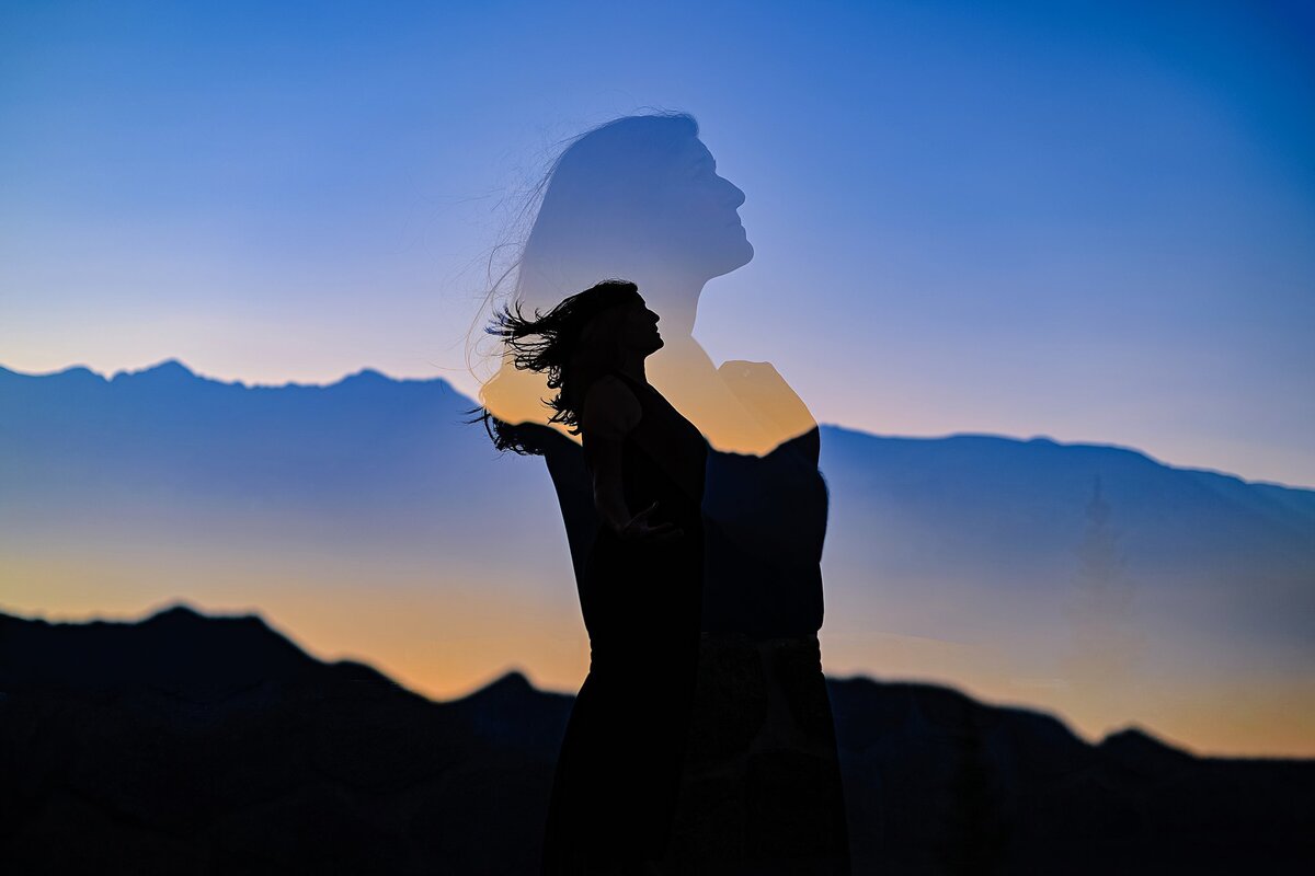 double exposure silhouette of woman with hair blowing in front of mountain range