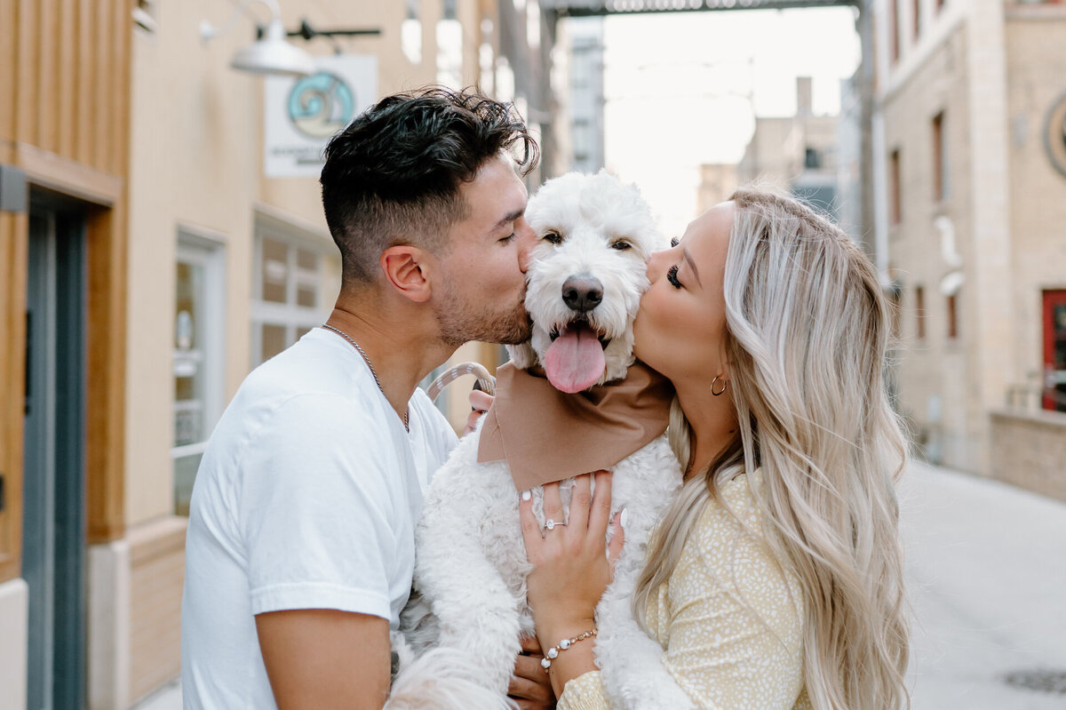engaged couple kissing their dog