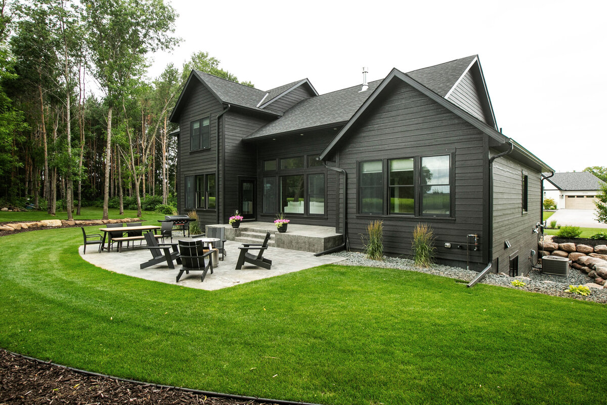 Exterior view of custom home in Otsego, Minnesota with black siding, large patio and windows built by Cornerstone Custom Builds