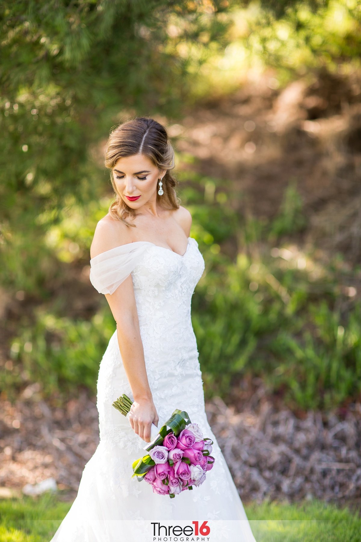 Bride looks down as she poses for wedding photographer