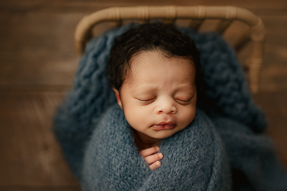 swaddled infant in blue knit blanket