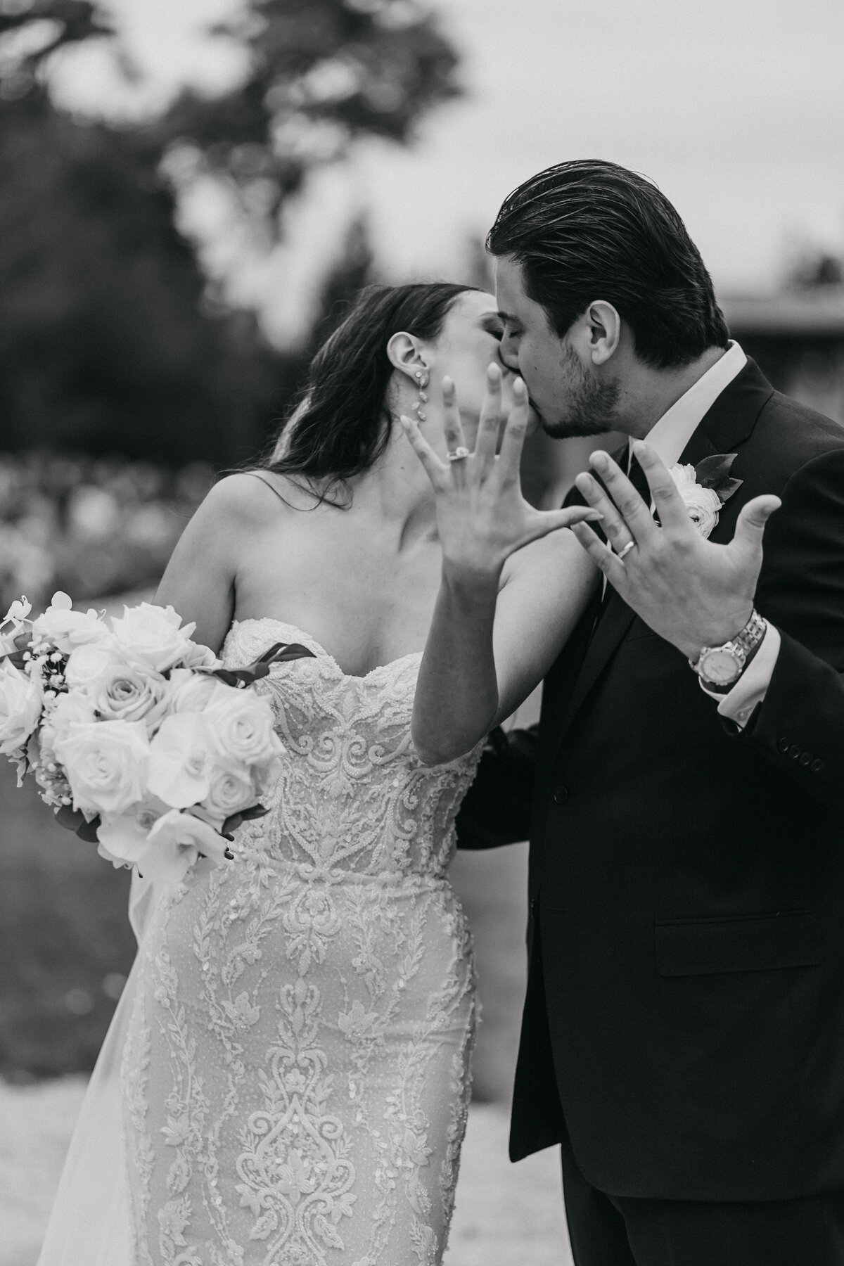bride and groom kiss and show off wedding bands