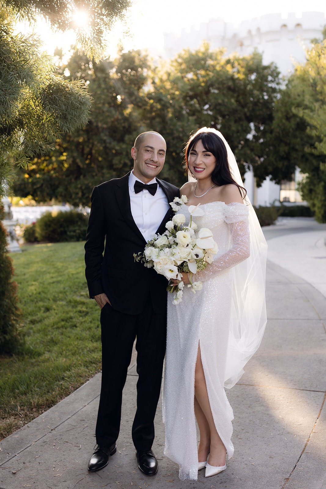 A bride and groom pose at golden hour, bathed in soft sunlight, with a scenic backdrop. A perfect example of cinematic wedding photography blending elegance and authenticity.