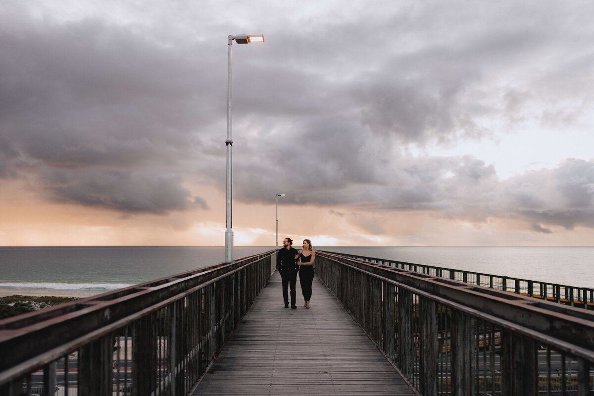 Couple walking on bridge with sunset in the back ground