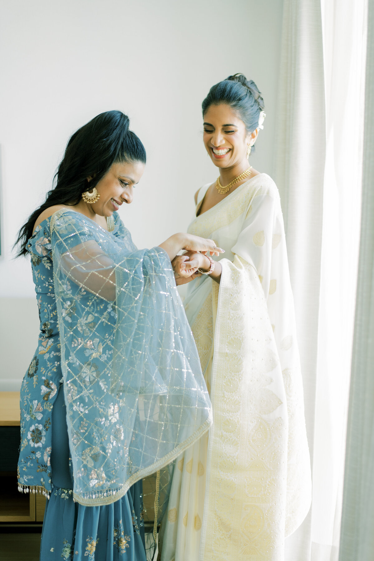 Bridesmaid helps bride while getting dressed