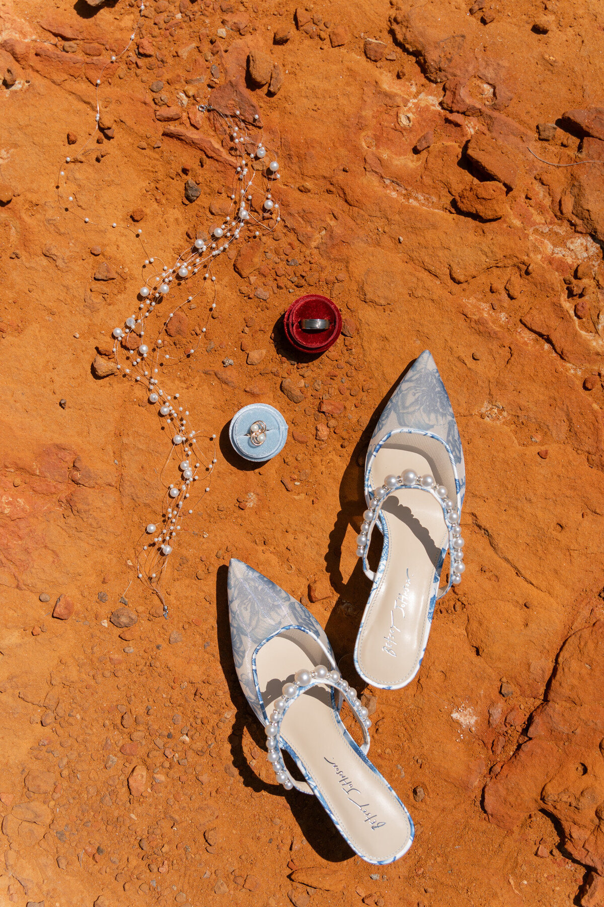Vibrant red dirt makes the perfect backdrop to this elopement flat-lay featuring blue shoes
