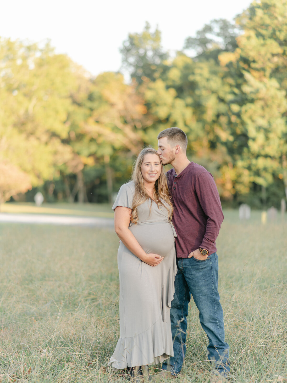 Young Dad kissing expecting Mom on the forehead.