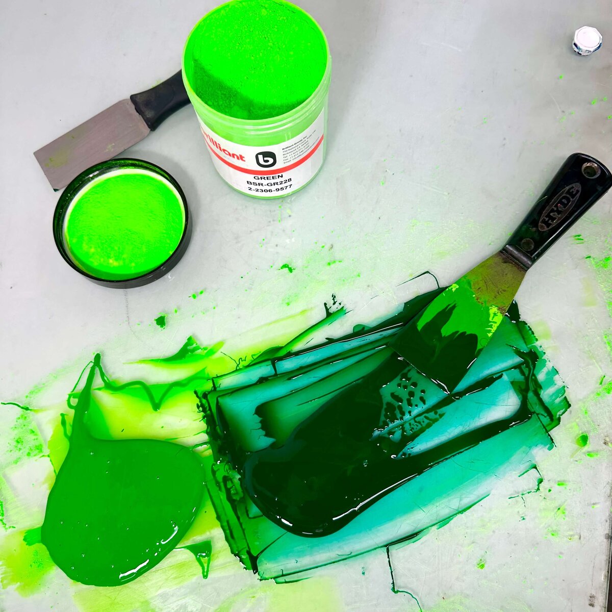 Bright green powdered pigment and a jar of freshly mixed green ink with palette knife, showcasing the transformation from powder to print-ready.