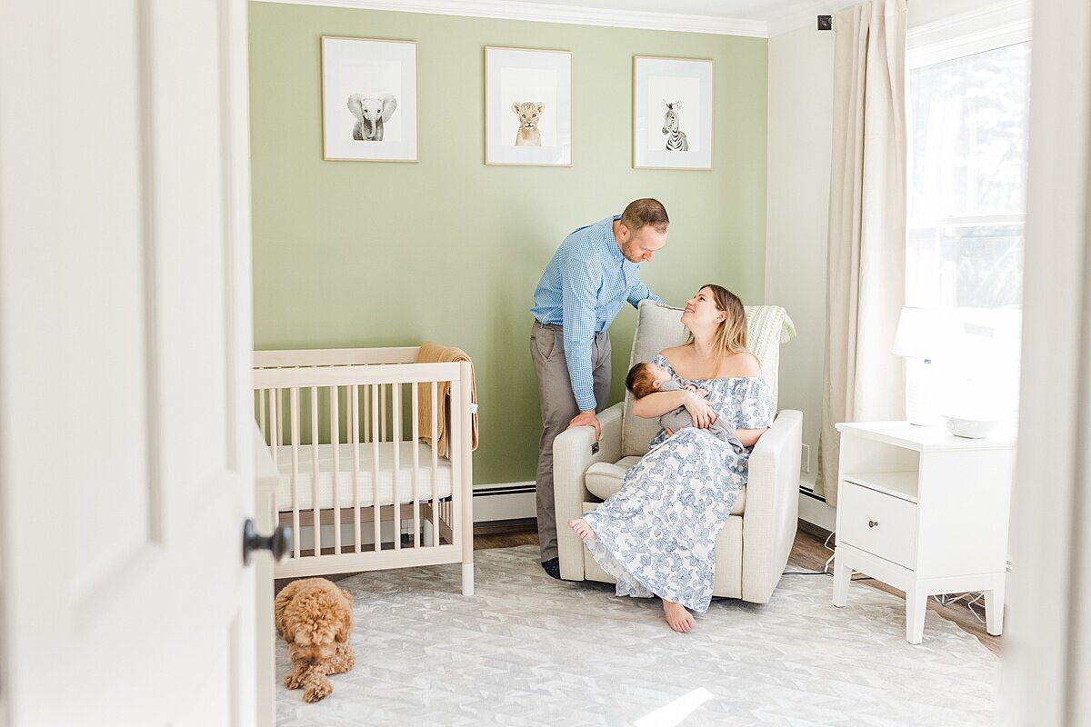 Family sits with dog in nursery during in home newborn photo session with Sara Sniderman Photography  in Natick Massachusetts