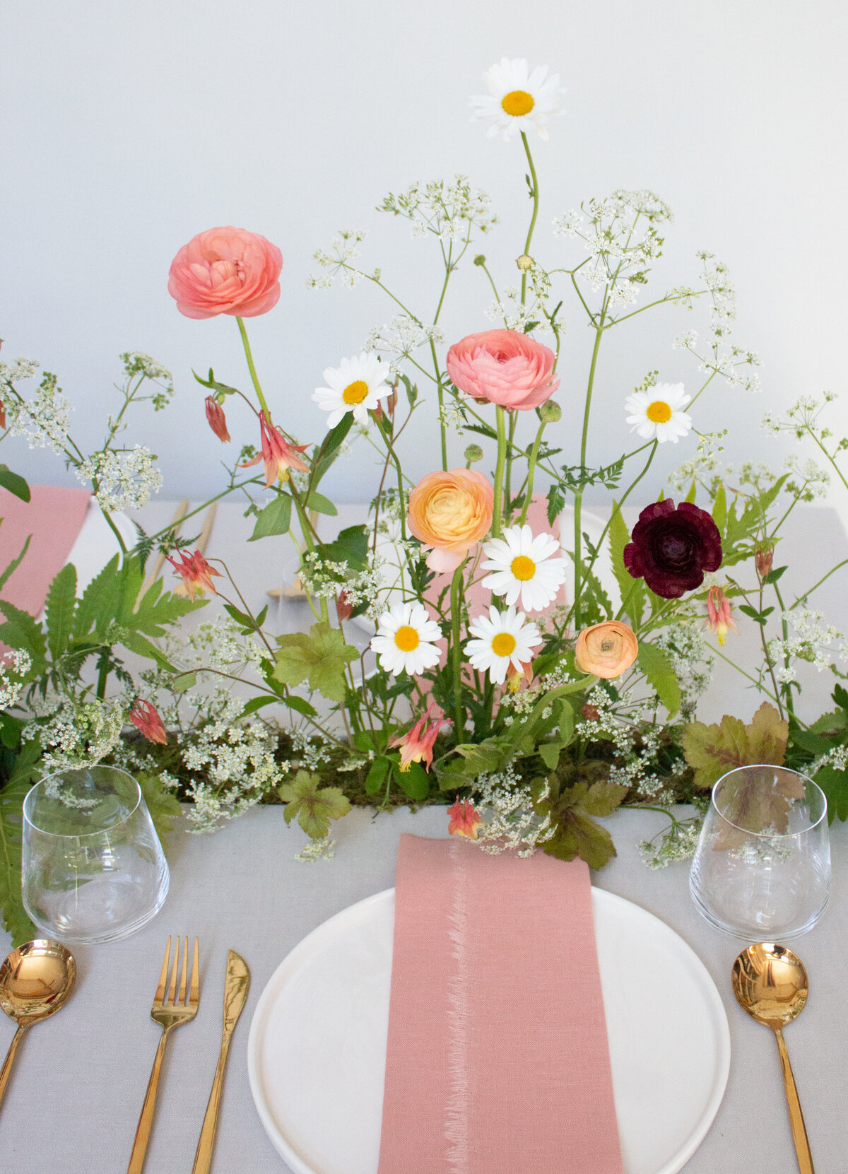 A low centrepiece of bright, organic spring flowers lines a table at a Montreal wedding reception.
